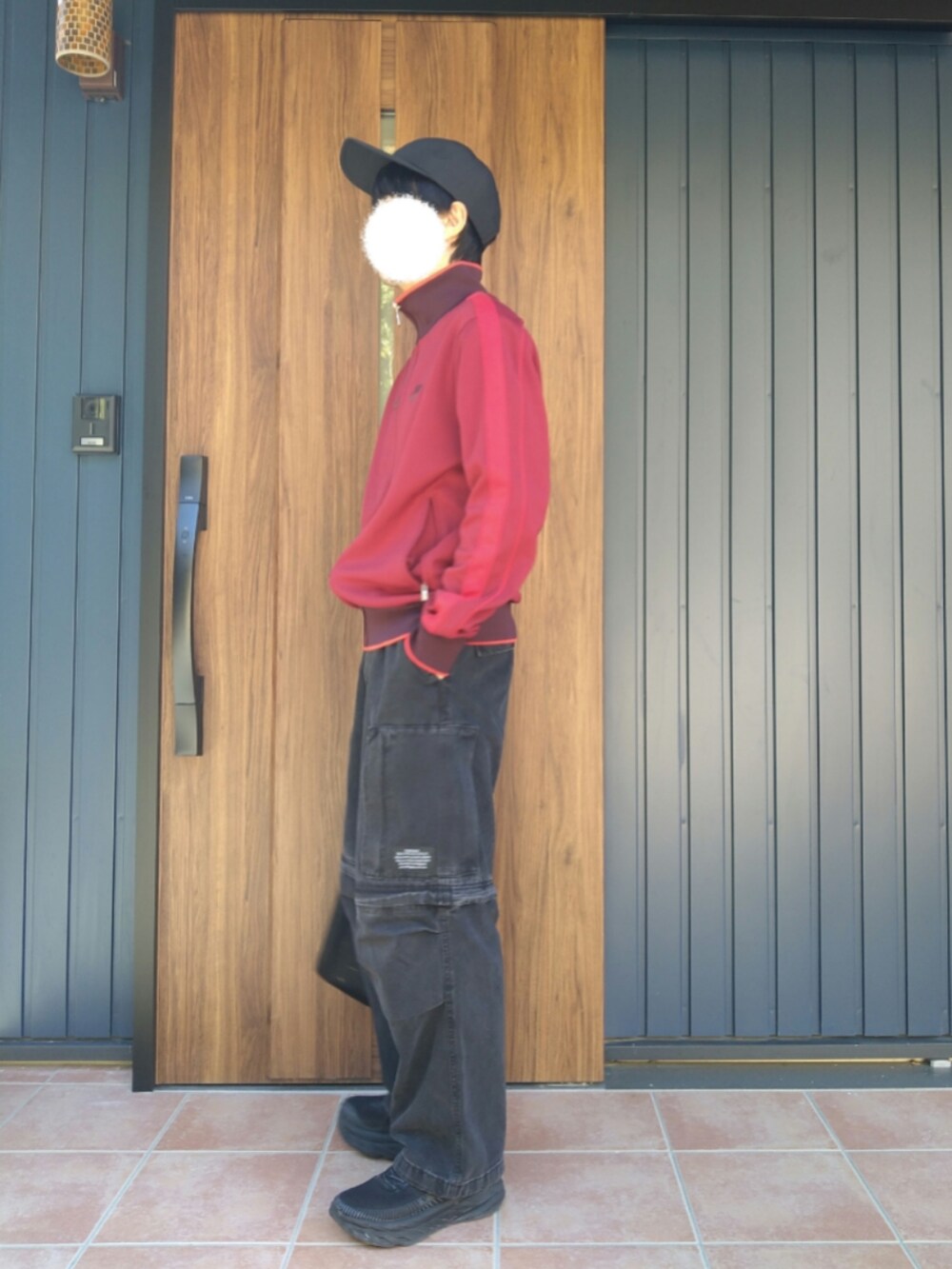 ブラック系のスニーカー、レッド系のジャージ、ブラック系のデニムパンツを着用したメンズの冬コーディネートの2枚目の写真