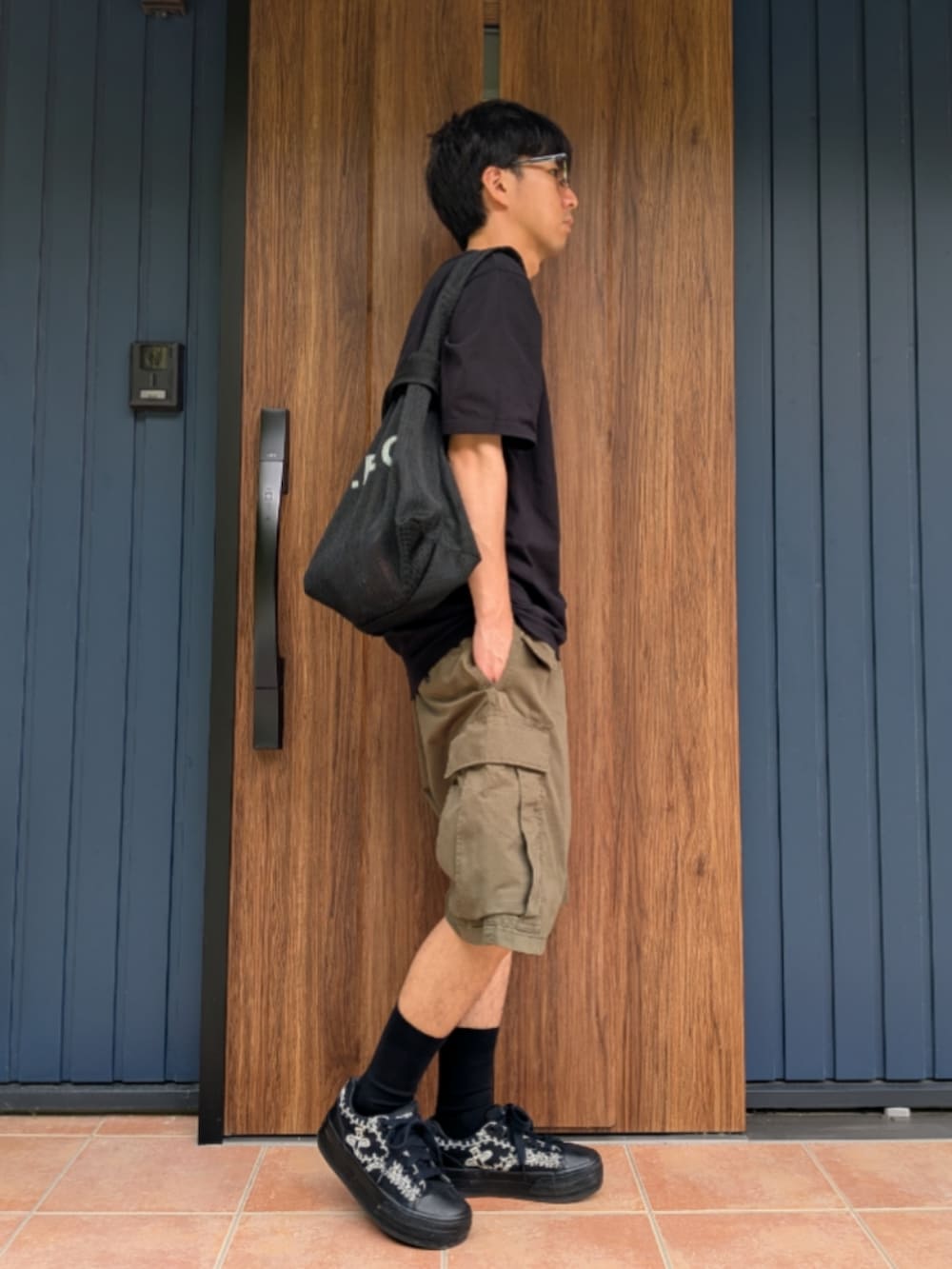 ブラック系のスニーカー、グリーン系のカーゴパンツ、ブラック系のショルダーバッグを着用したメンズの夏コーディネートの2枚目の写真