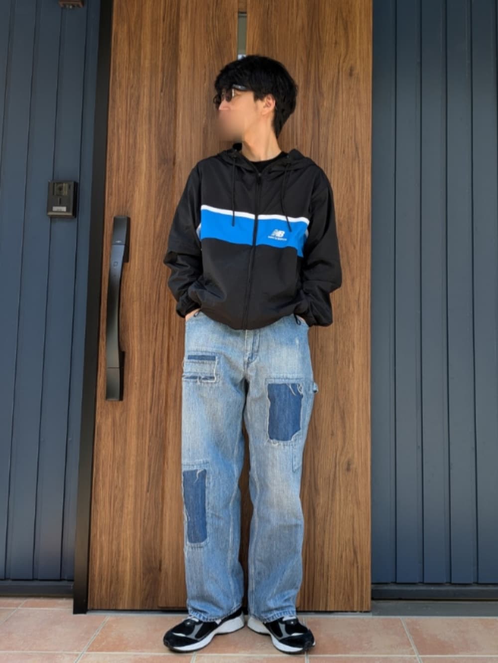 ブラック系のスニーカー、ブルー系のデニムパンツ、ブラック系のナイロンジャケットを着用したメンズの春コーディネートの2枚目の写真