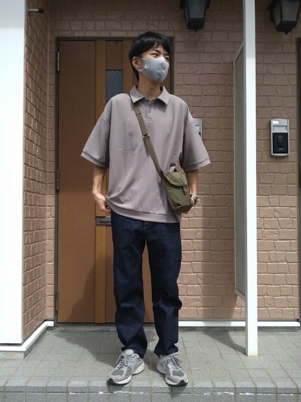 ベージュ系のポロシャツ、ブルー系のデニムパンツ、グレー系のスニーカーを着用したメンズの秋コーディネートの2枚目の写真