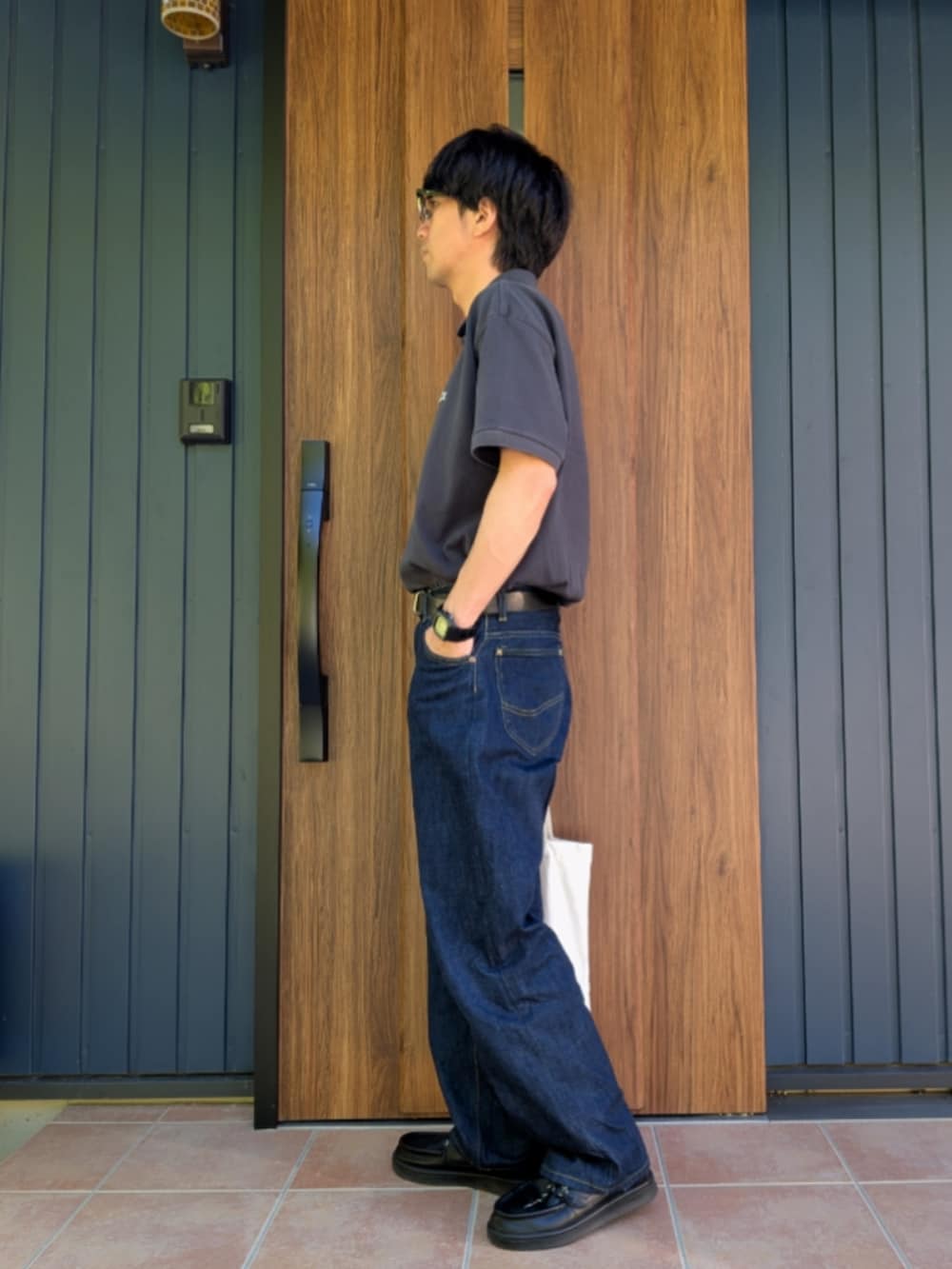 ブラック系のスニーカー、ブルー系のデニムパンツ、グレー系のポロシャツを着用したメンズの夏コーディネートの3枚目の写真
