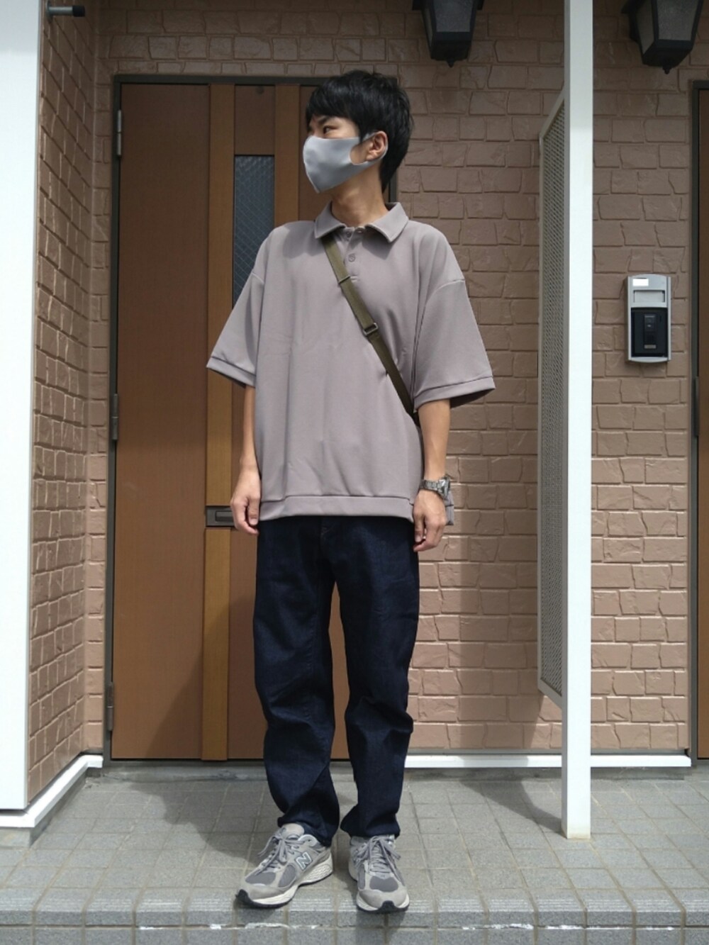 ベージュ系のポロシャツ、ブルー系のデニムパンツ、グレー系のスニーカーを着用したメンズの秋コーディネートの3枚目の写真