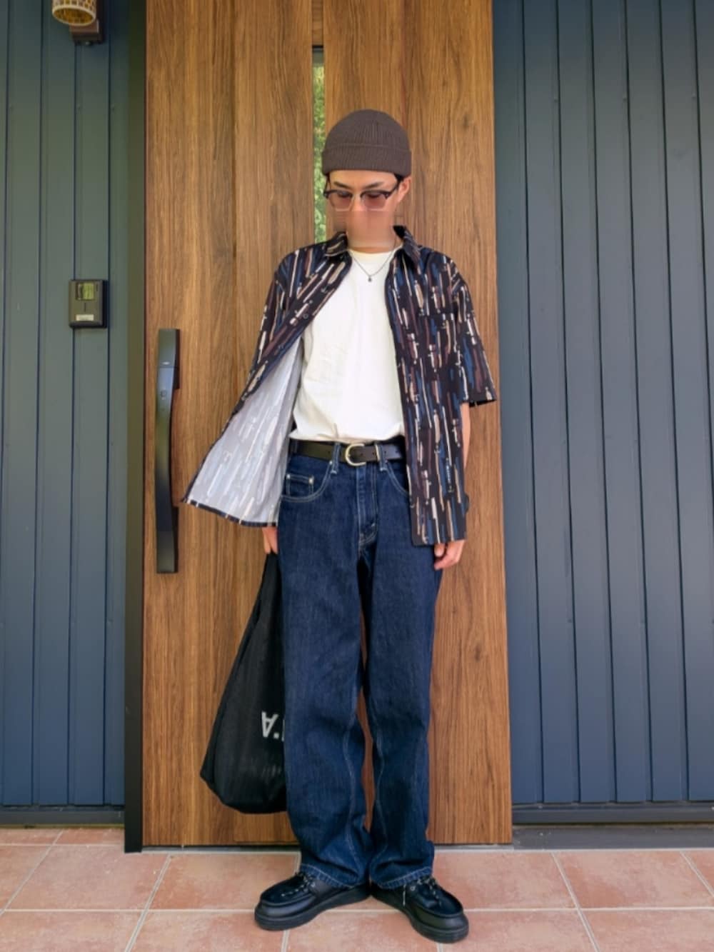 ブラック系のスニーカー、ブルー系のデニムパンツ、ホワイト系のTシャツ/カットソーを着用したメンズの夏コーディネートの4枚目の写真