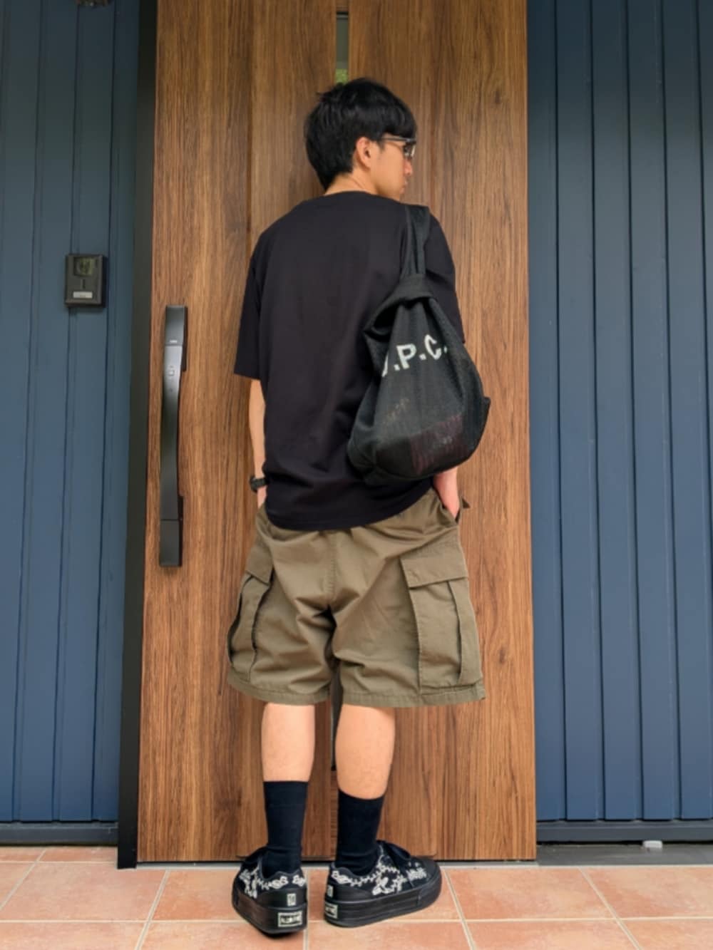 ブラック系のスニーカー、グリーン系のカーゴパンツ、ブラック系のショルダーバッグを着用したメンズの夏コーディネートの3枚目の写真
