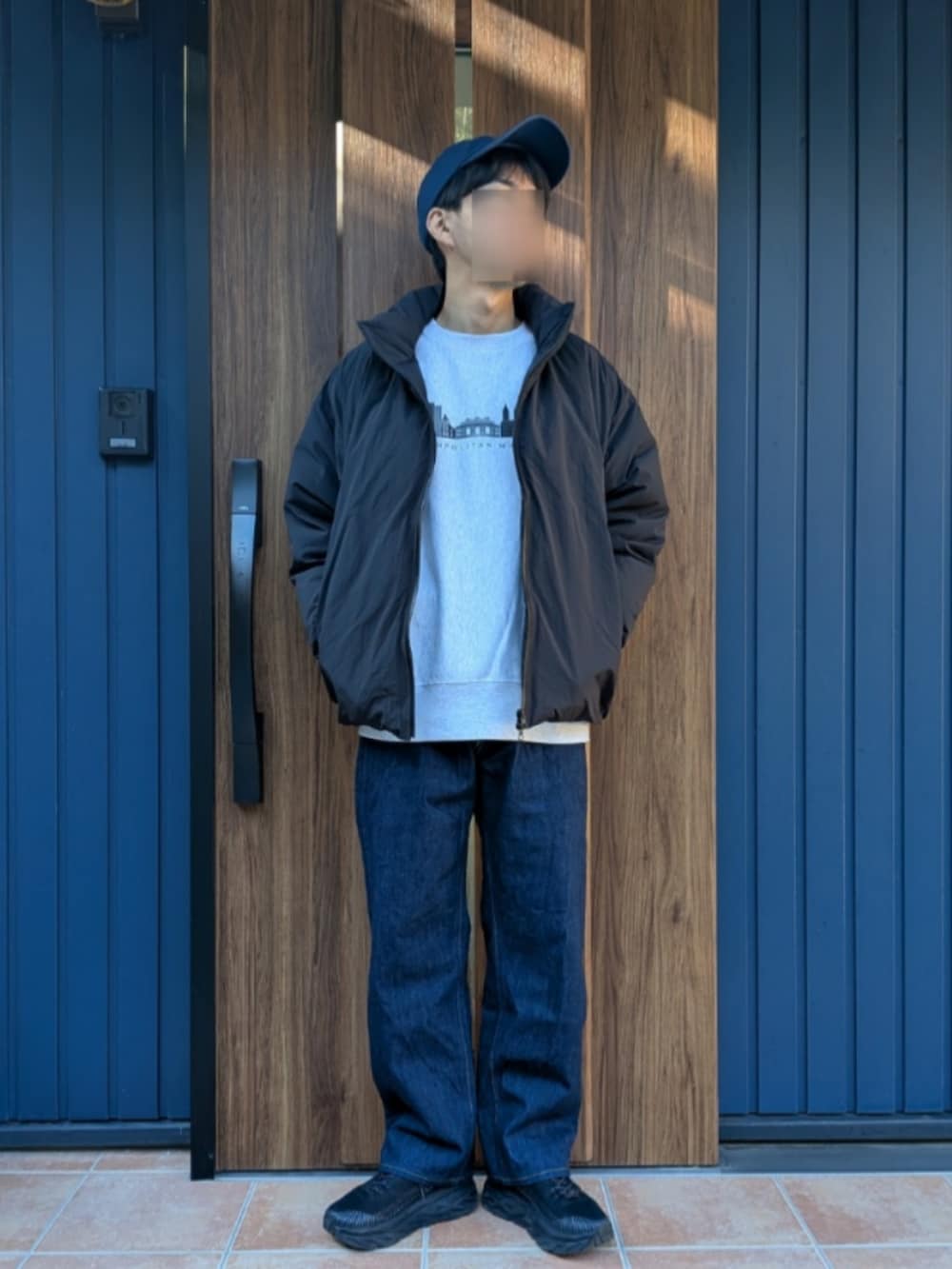 ブラック系のスニーカー、ブルー系のデニムパンツ、ブラック系のダウンジャケット/コートを着用したメンズの冬コーディネートの2枚目の写真