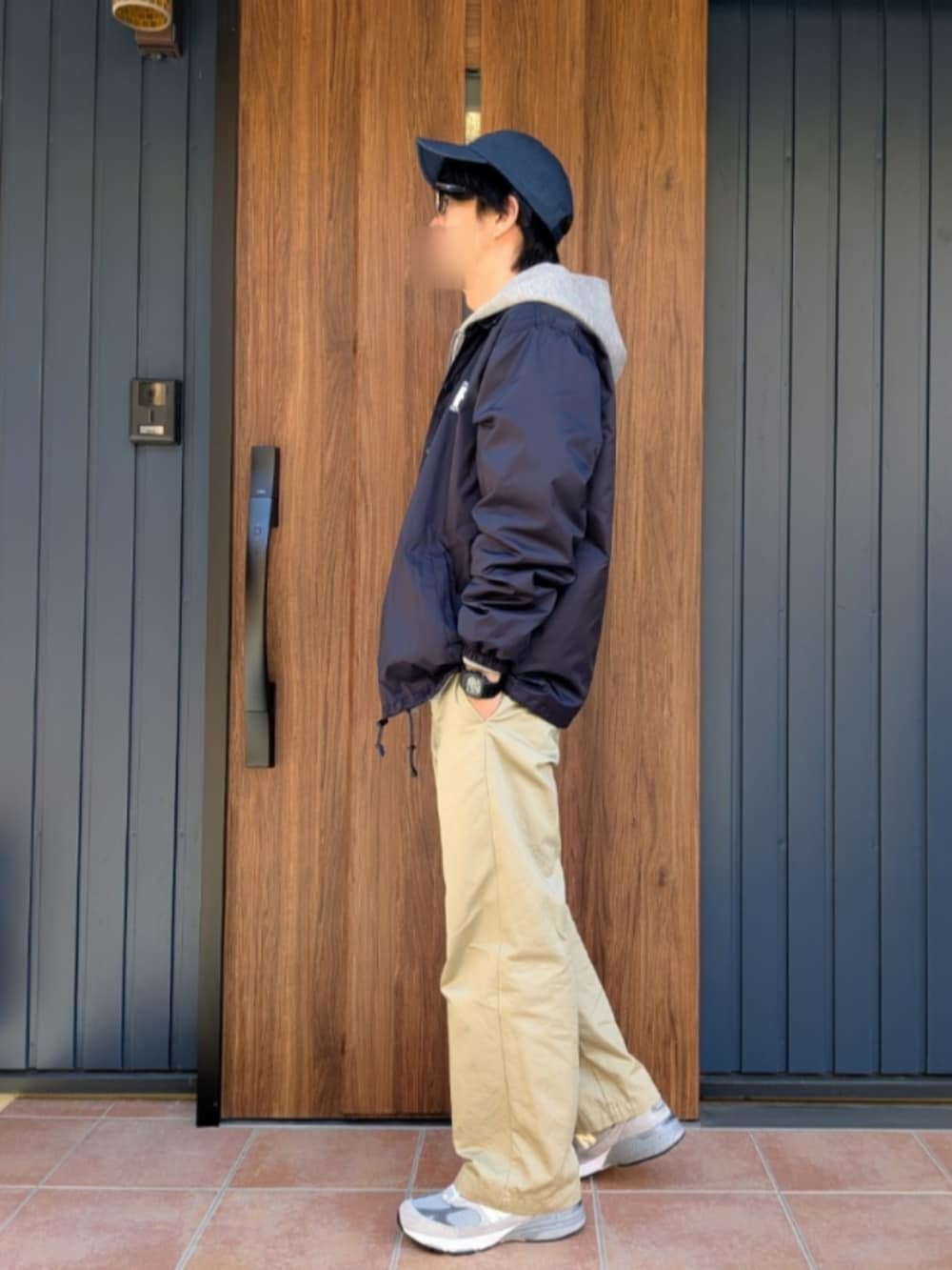 グレー系のスニーカー、ベージュ系のチノパンツ、ブルー系のナイロンジャケットを着用したメンズの冬コーディネートの2枚目の写真