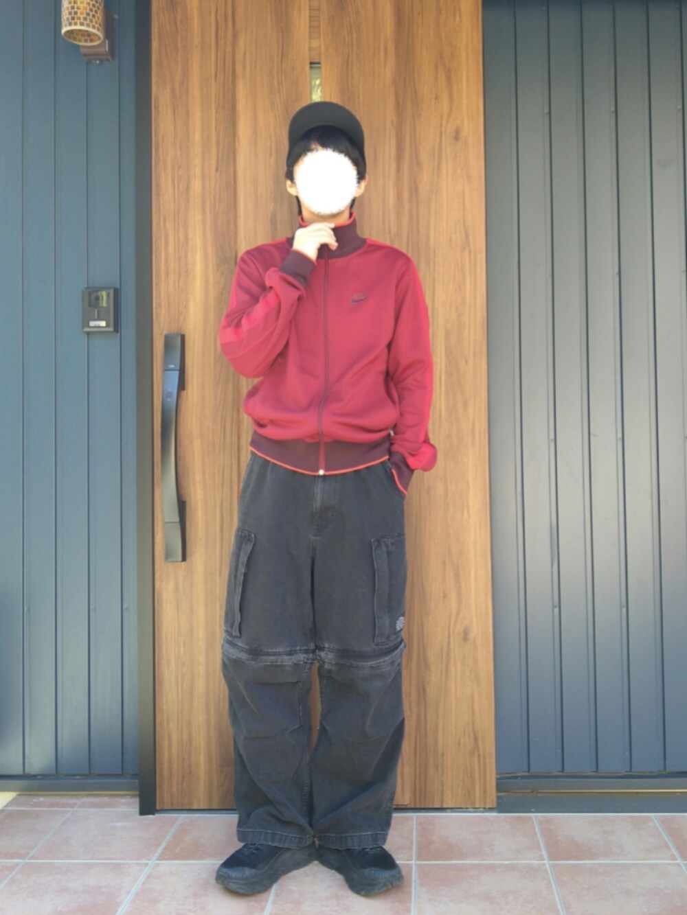 ブラック系のスニーカー、レッド系のジャージ、ブラック系のデニムパンツを着用したメンズの冬コーディネートの4枚目の写真