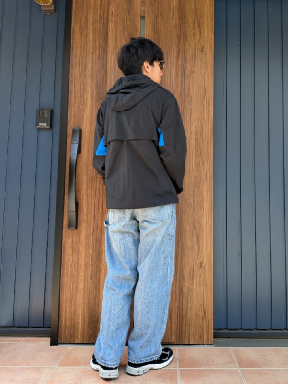 ブラック系のスニーカー、ブルー系のデニムパンツ、ブラック系のナイロンジャケットを着用したメンズの春コーディネートの4枚目の写真