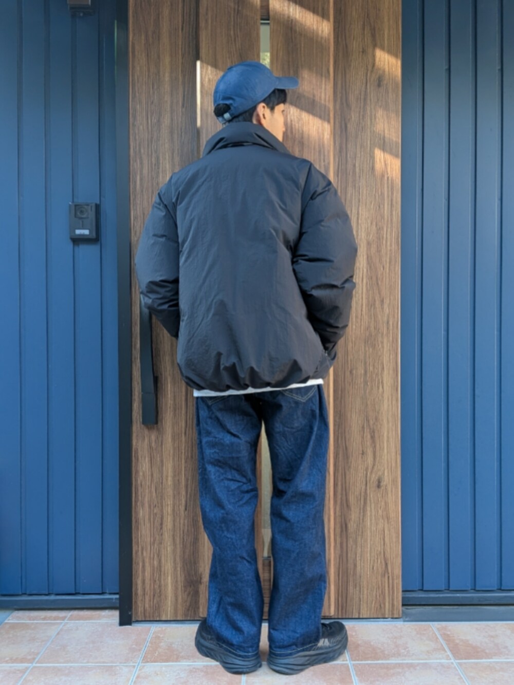 ブラック系のスニーカー、ブルー系のデニムパンツ、ブラック系のダウンジャケット/コートを着用したメンズの冬コーディネートの4枚目の写真