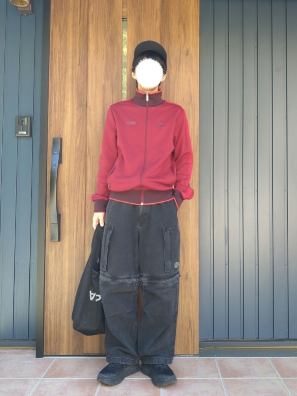 ブラック系のスニーカー、レッド系のジャージ、ブラック系のデニムパンツを着用したメンズの冬コーディネートの5枚目の写真