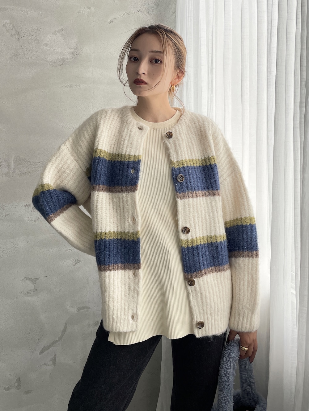 ホワイト系のカーディガン/ボレロ、ブラック系のデニムパンツを着用したレディースの秋コーディネートの2枚目の写真