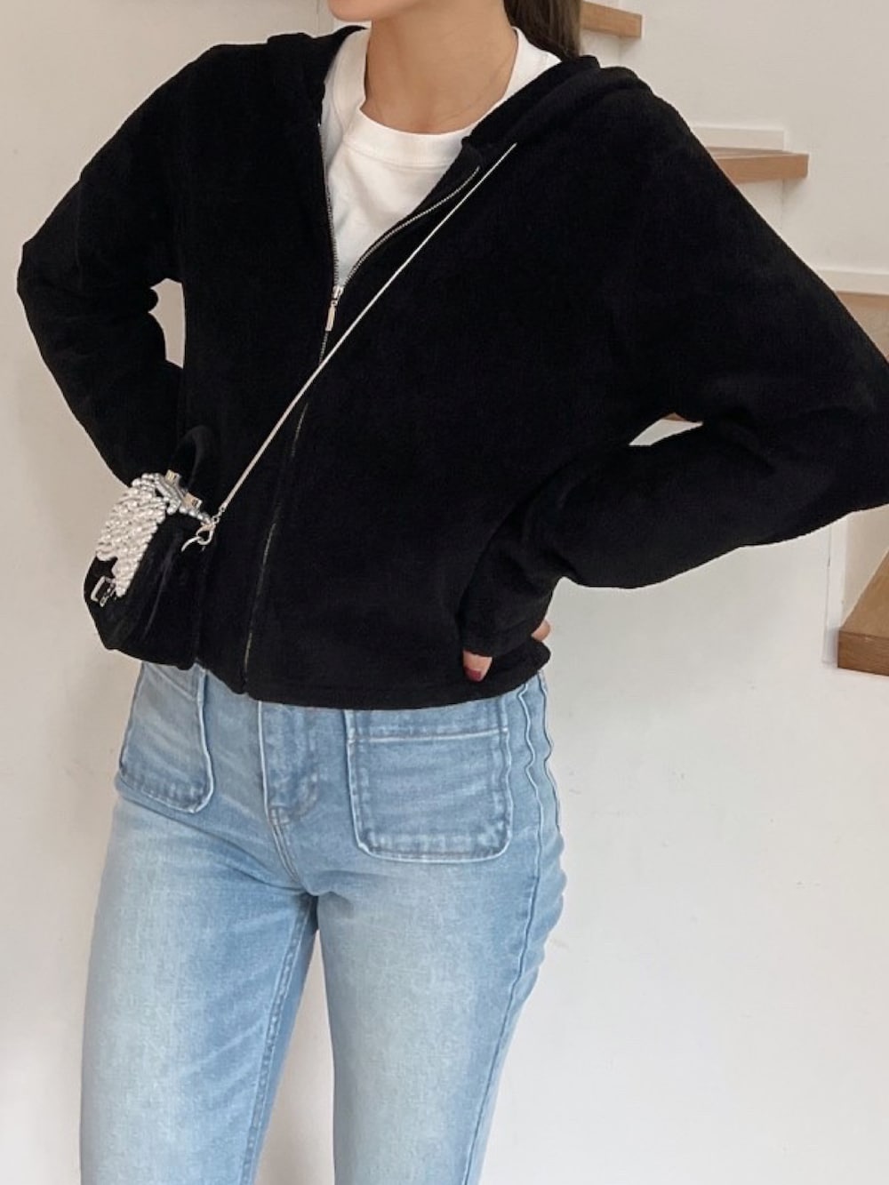 ブラック系のパーカー、ブルー系のデニムパンツを着用したレディースの冬コーディネートの2枚目の写真