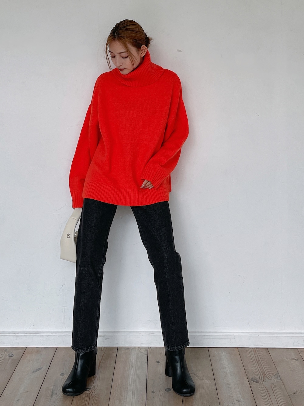 オレンジ系のニット/セーター、ブラック系のデニムパンツ、ブラック系のブーツを着用したレディースの秋コーディネートの2枚目の写真