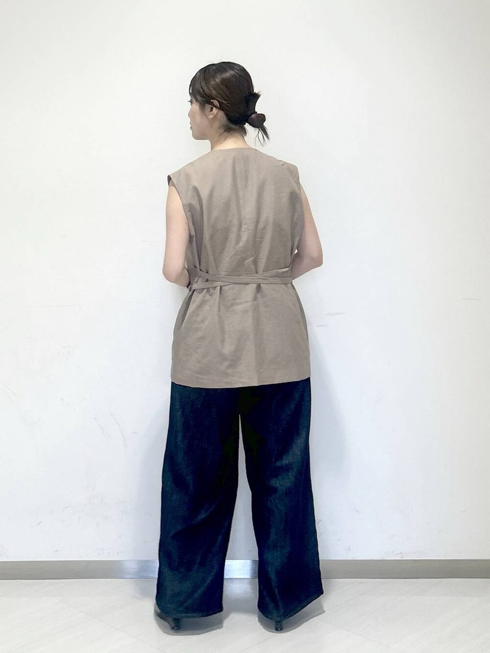 ブルー系のデニムパンツ、ブラック系のサンダル、グレー系のベストを着用したレディースの夏コーディネートの3枚目の写真