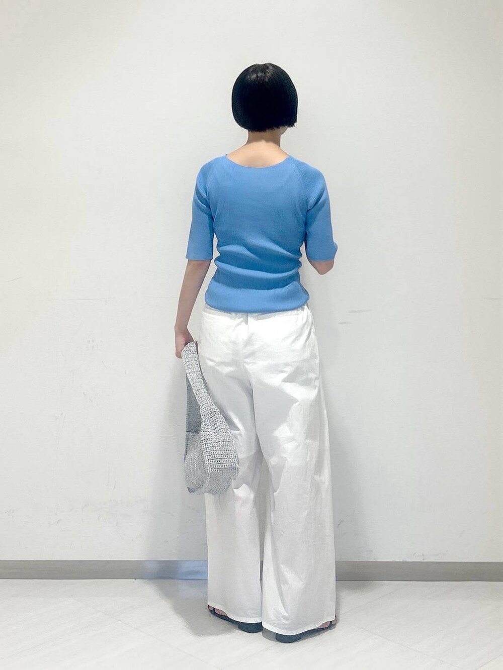 ブルー系のニット/セーター、シルバー系のハンドバッグ、ホワイト系のその他パンツを着用したレディースの夏コーディネートの3枚目の写真
