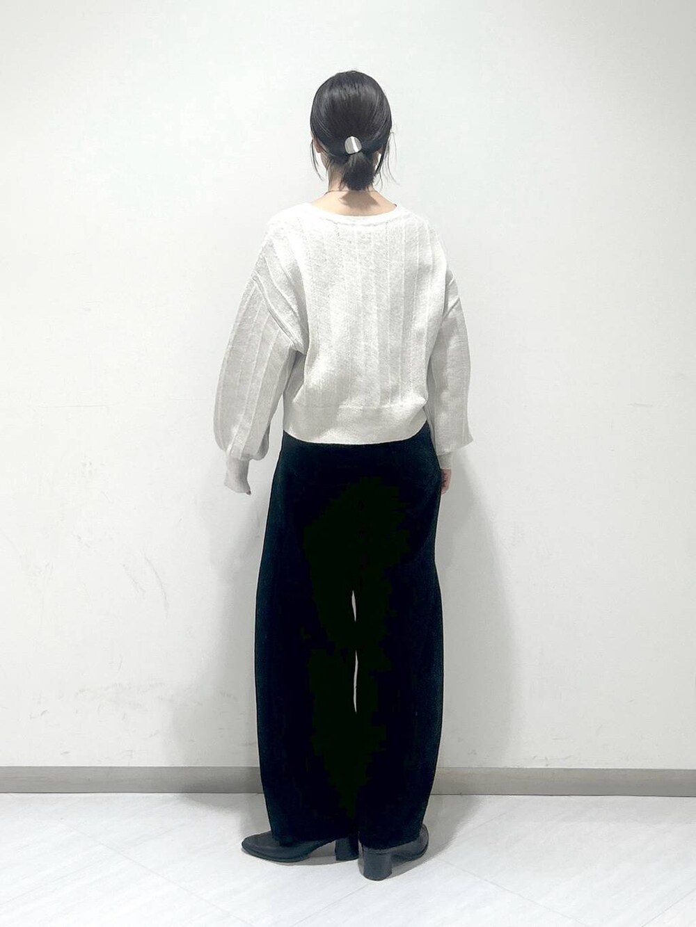 ブラック系のデニムパンツ、ブラック系のブーツ、ホワイト系のカーディガン/ボレロを着用したレディースの冬コーディネートの3枚目の写真