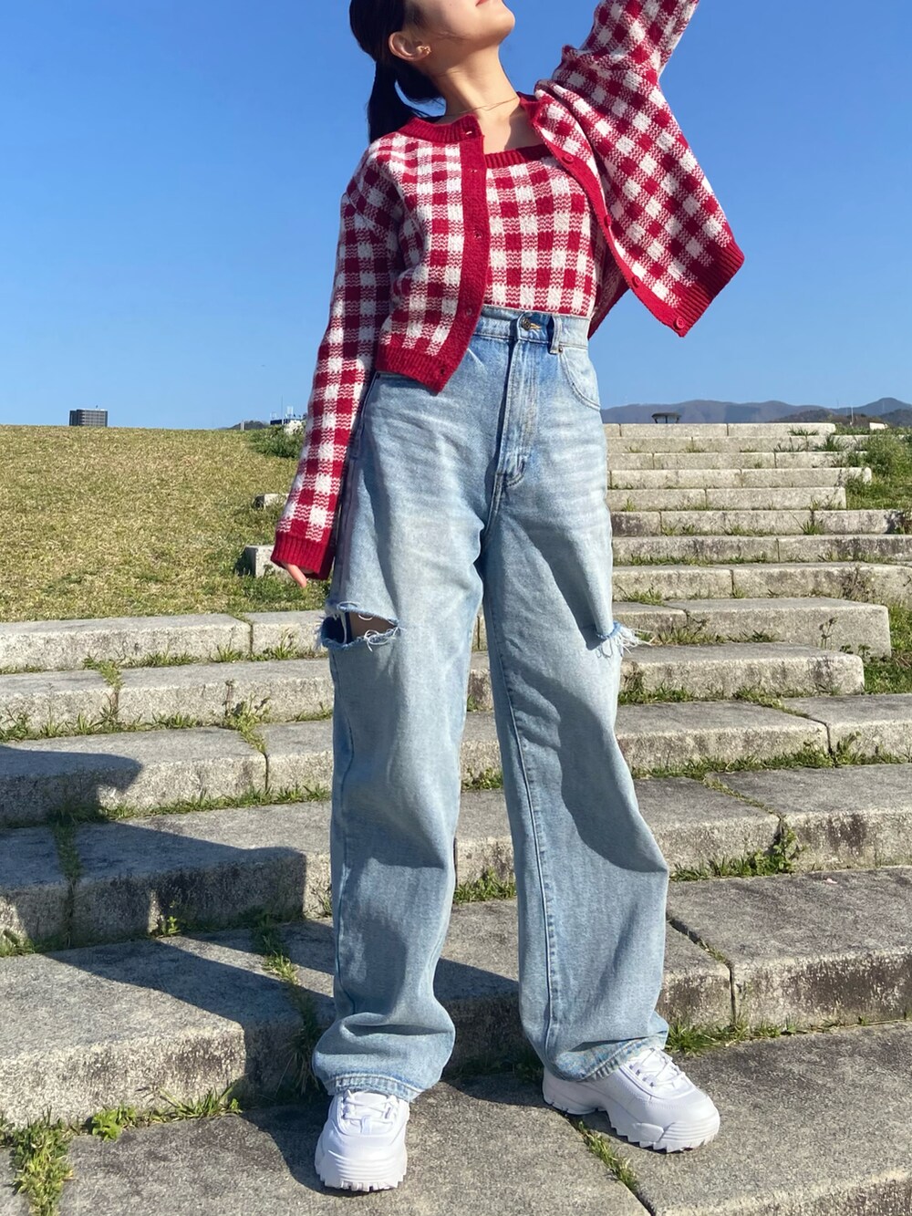 レッド系のトップス、ブルー系のデニムパンツを着用したレディースの春コーディネートの5枚目の写真