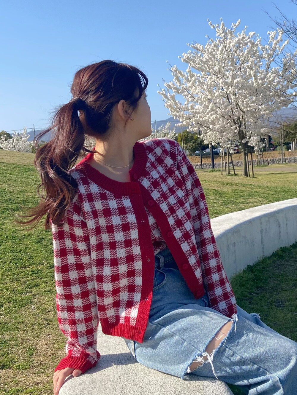 レッド系のトップス、ブルー系のデニムパンツを着用したレディースの春コーディネートの2枚目の写真