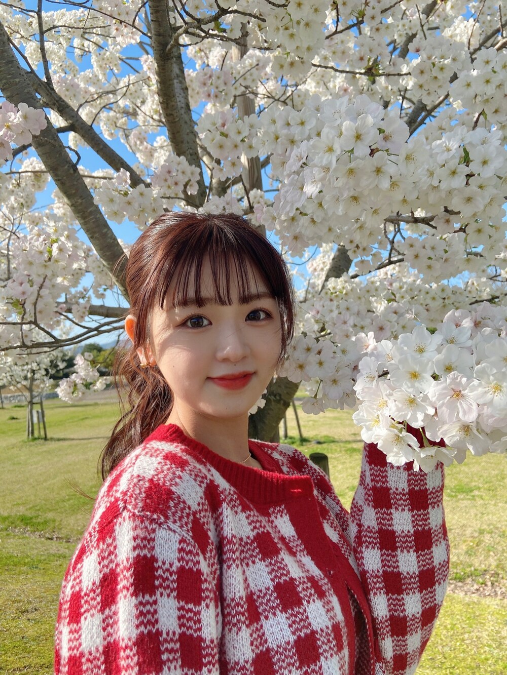 レッド系のトップス、ブルー系のデニムパンツを着用したレディースの春コーディネートの3枚目の写真