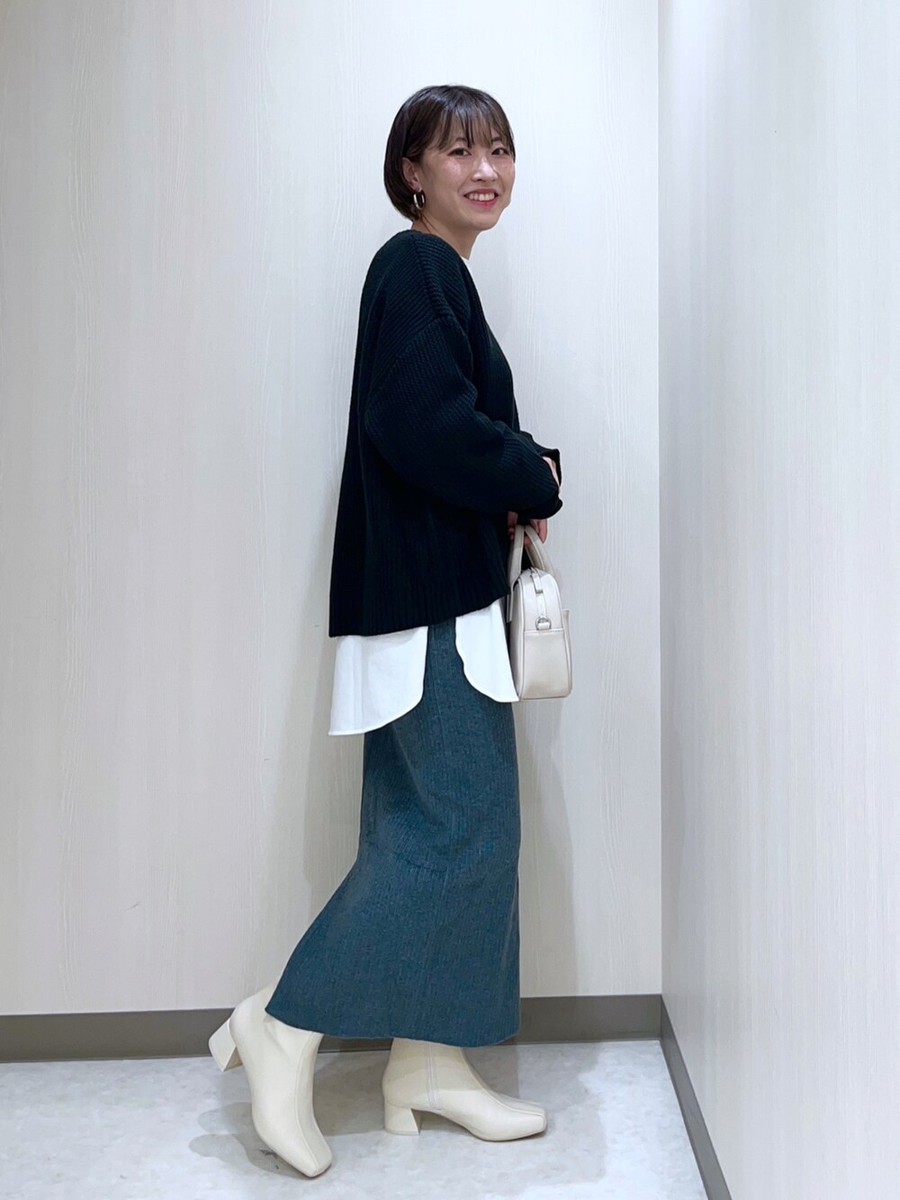 ブラック系のニット/セーター、ホワイト系のTシャツ/カットソー、グリーン系のスカートを着用したレディースの秋コーディネートの2枚目の写真