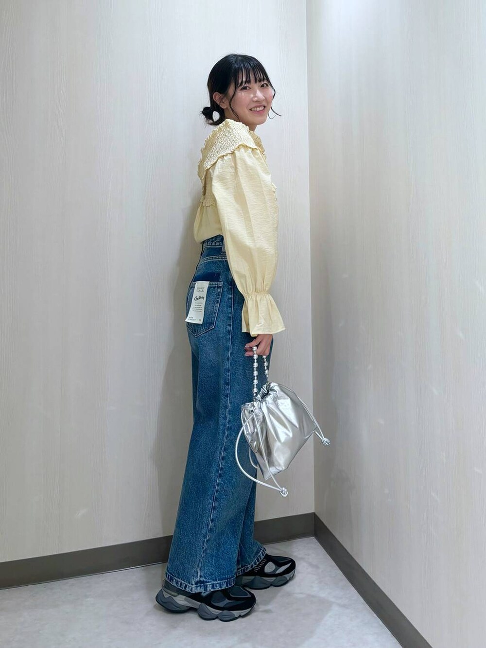 ブルー系のデニムパンツ、シルバー系のショルダーバッグ、イエロー系のシャツ/ブラウスを着用したレディースの冬コーディネートの2枚目の写真