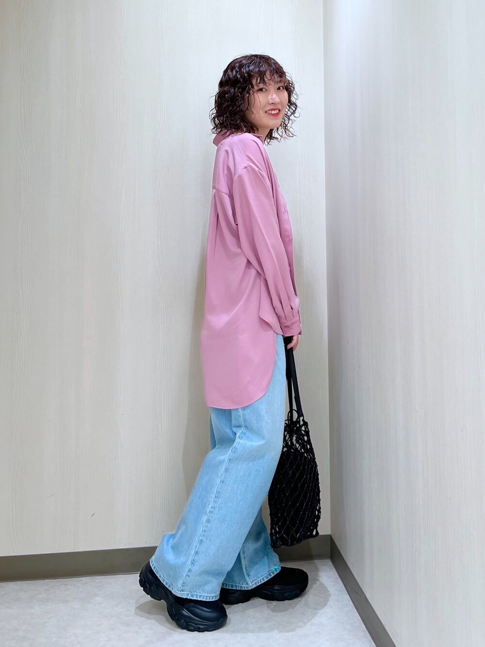 ピンク系のトップス、ブルー系のデニムパンツ、ブラック系のタンクトップを着用したレディースの春コーディネートの3枚目の写真