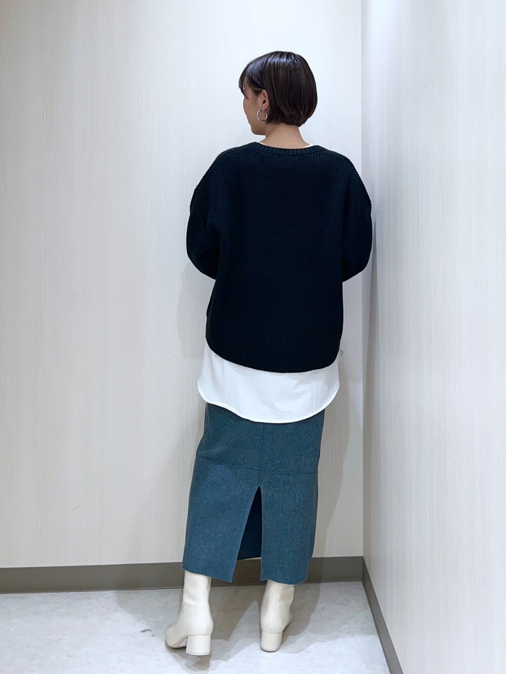 ブラック系のニット/セーター、ホワイト系のTシャツ/カットソー、グリーン系のスカートを着用したレディースの秋コーディネートの3枚目の写真