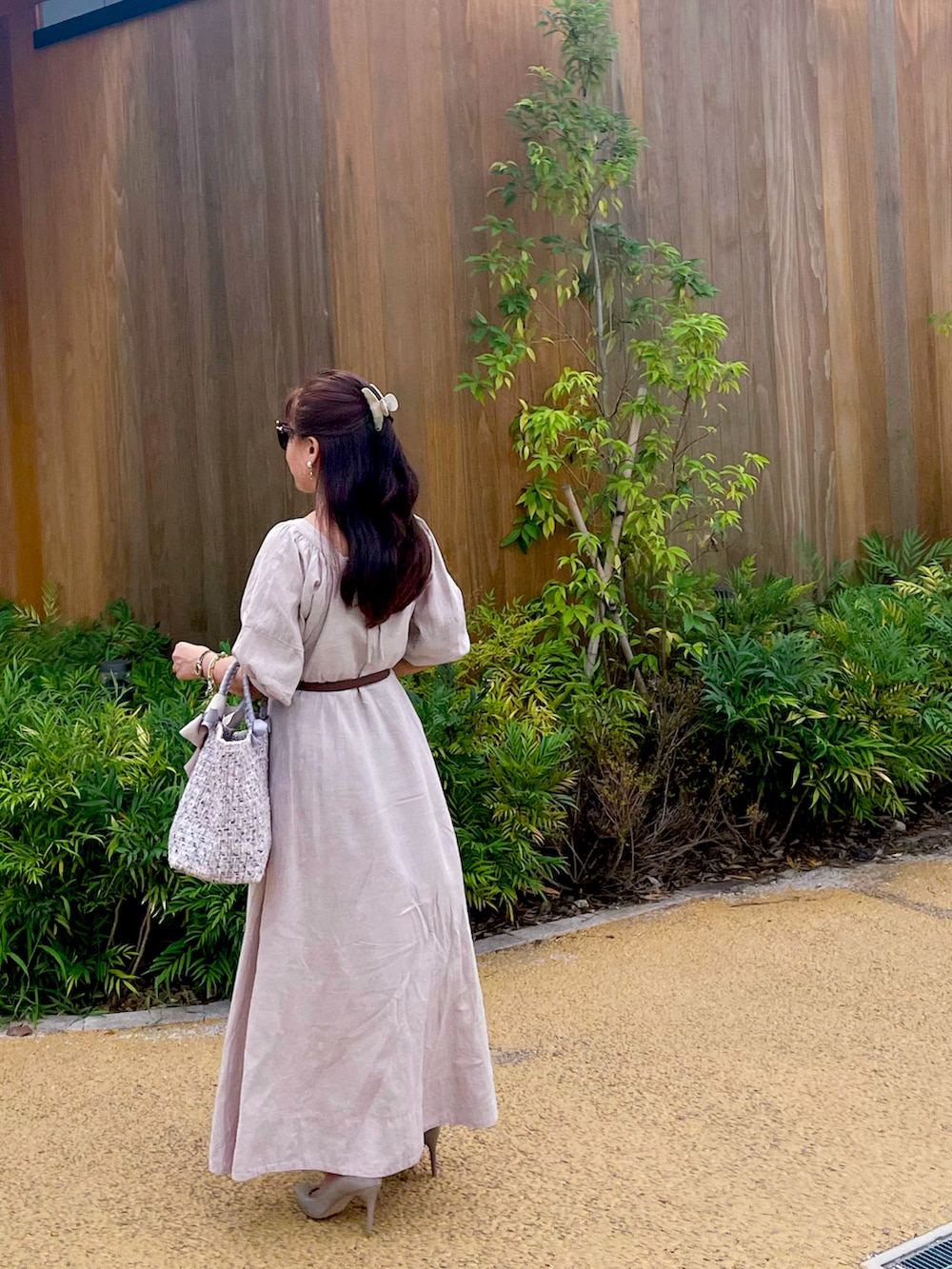 ピンク系のハンドバッグ、ベージュ系のワンピース、その他のパンプスを着用したレディースの夏コーディネートの3枚目の写真