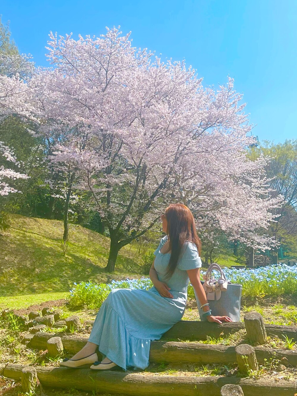 ブルー系のワンピースを着用したレディースの春コーディネートの2枚目の写真