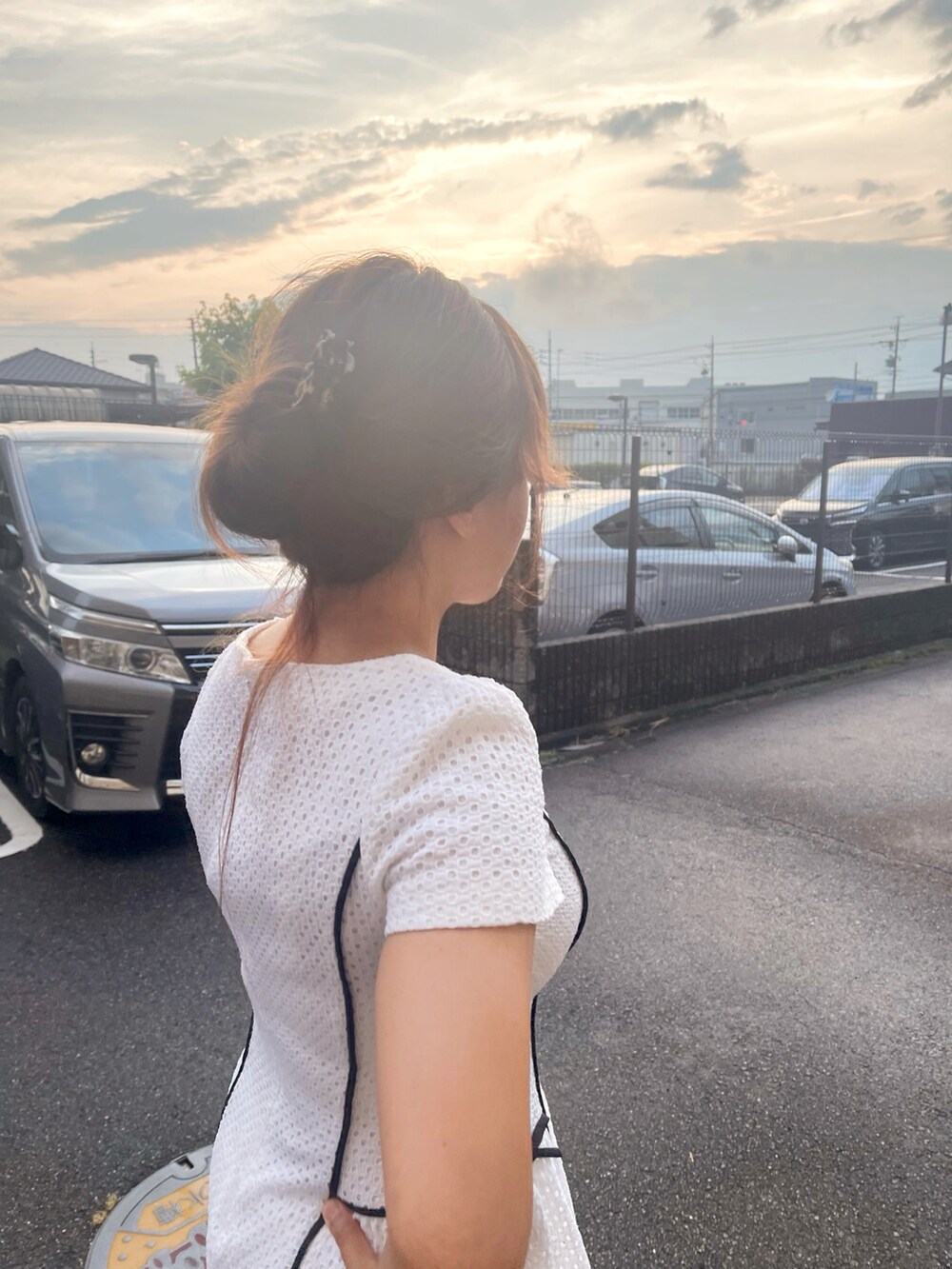 ブラック系のハンドバッグ、ホワイト系のワンピース、ブラウン系のバレッタ/ヘアクリップを着用したレディースの夏コーディネートの2枚目の写真