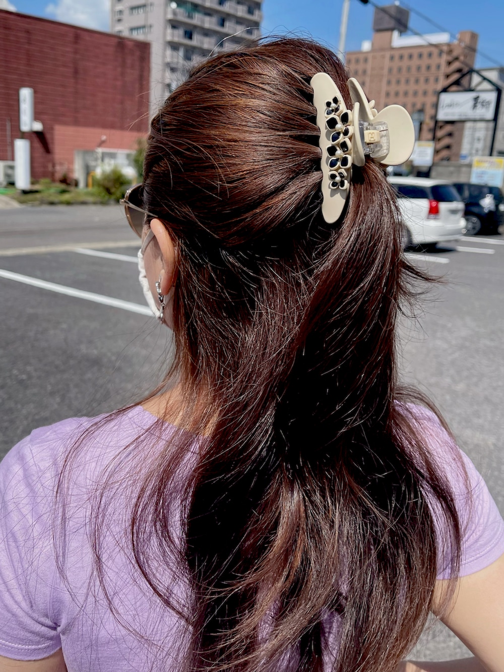 ブラック系のハンドバッグ、ブラック系のパンプス、パープル系のTシャツ/カットソーを着用したレディースの夏コーディネートの2枚目の写真