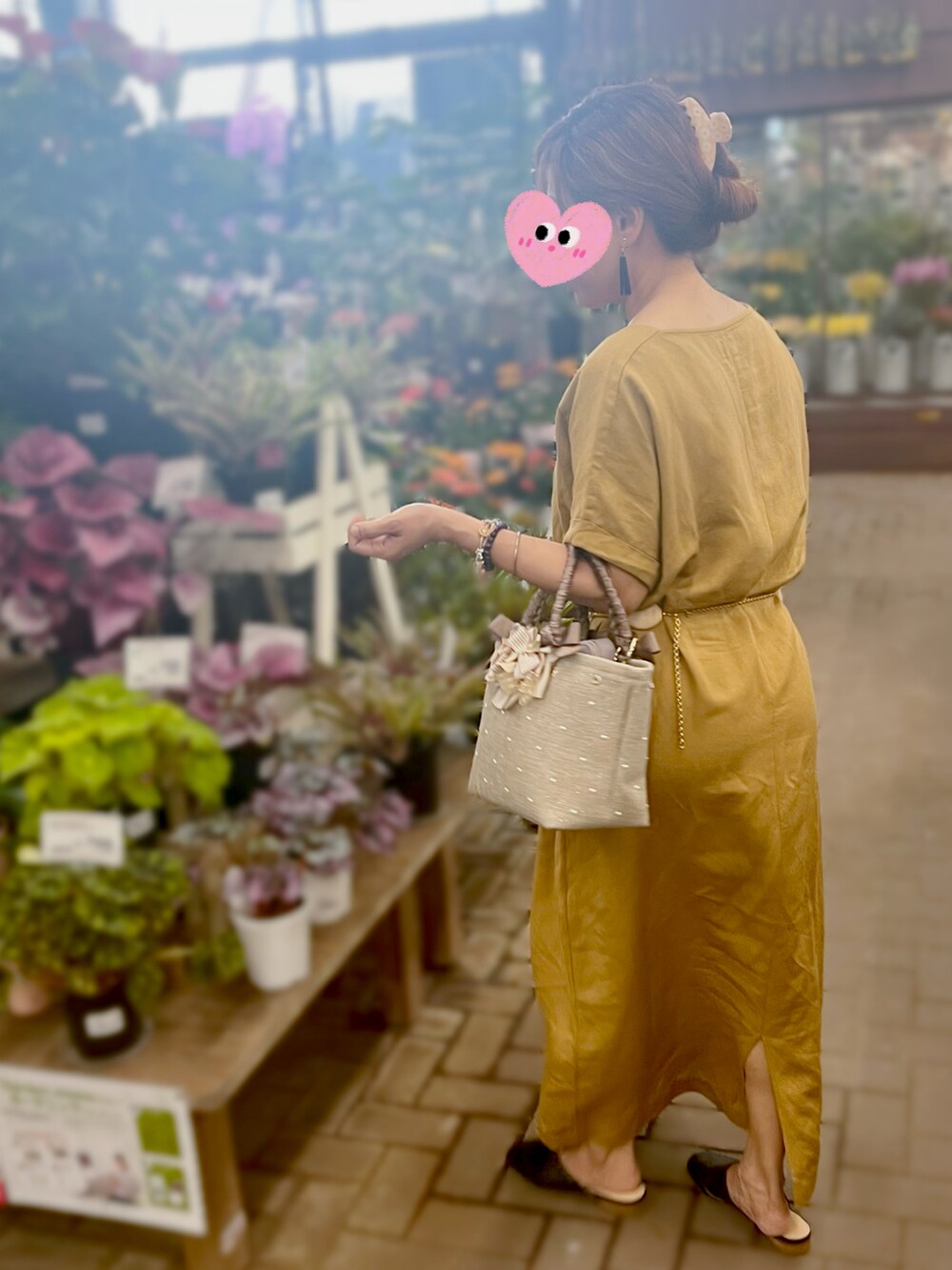 ベージュ系のハンドバッグ、グリーン系のワンピース、ブラック系のシューズを着用したレディースの夏コーディネートの3枚目の写真