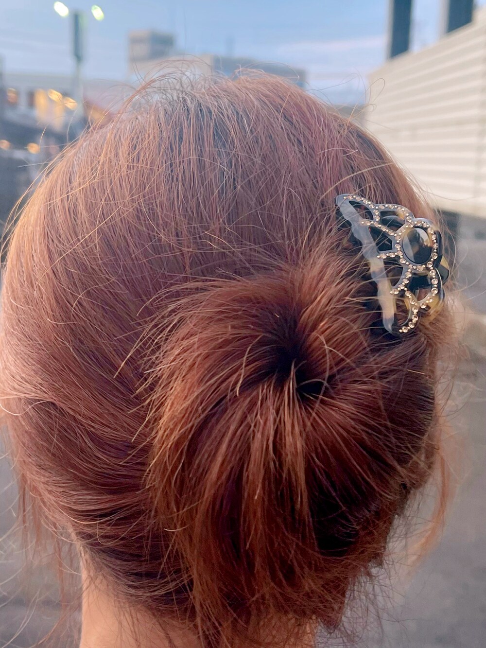 ブラック系のハンドバッグ、ホワイト系のワンピース、ブラウン系のバレッタ/ヘアクリップを着用したレディースの夏コーディネートの4枚目の写真