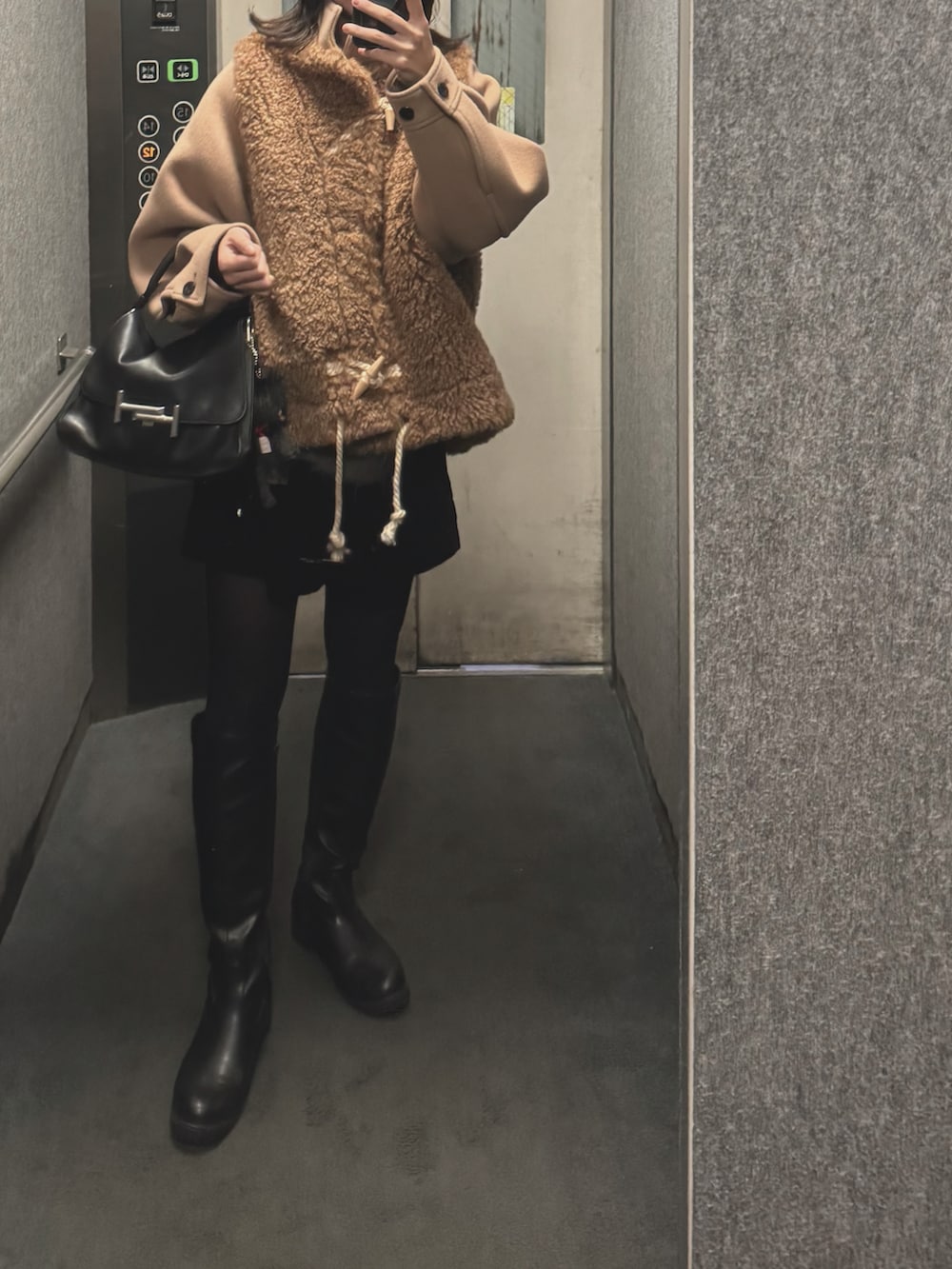 ブラウン系のダッフルコート、グレー系のニット/セーター、ブラック系のブーツを着用したレディースの冬コーディネートの2枚目の写真