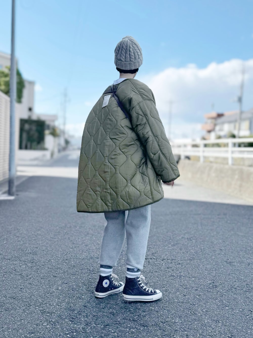 グリーン系のモッズコート、ホワイト系のニット/セーター、グレー系のその他パンツを着用したレディースの冬コーディネートの2枚目の写真