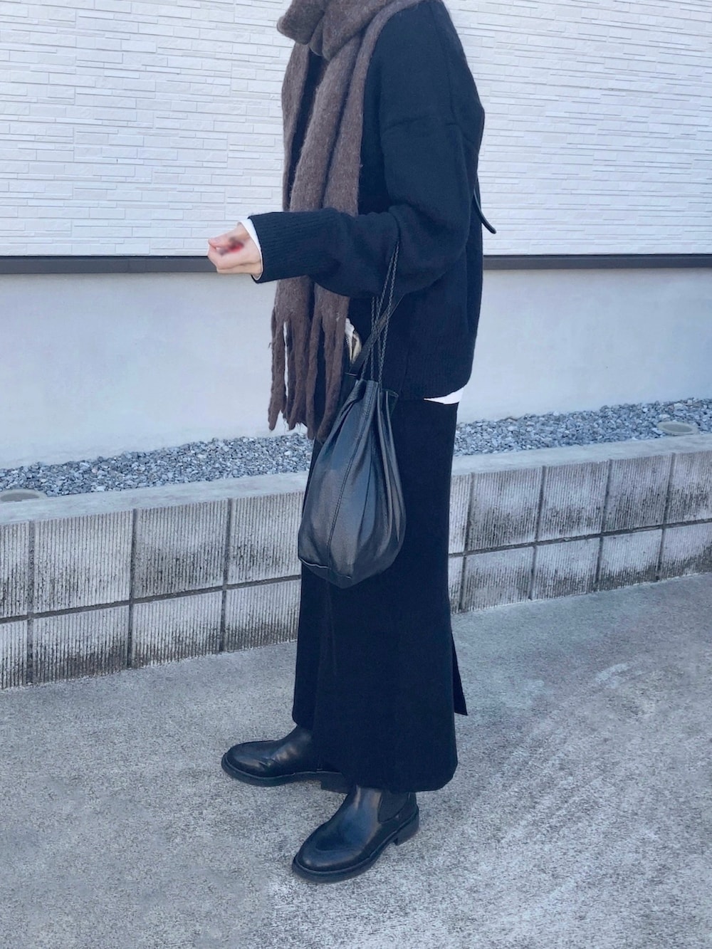 ブラック系のブーツ、ブラウン系のマフラーを着用したレディースの冬コーディネートの2枚目の写真