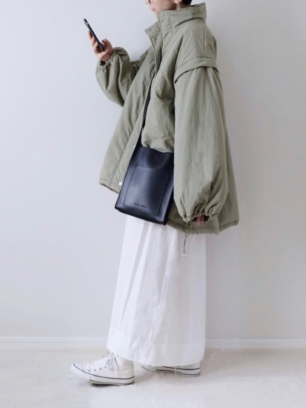 ブラック系のTシャツ/カットソー、ホワイト系のスカート、ホワイト系のスニーカーを着用したレディースの秋コーディネートの3枚目の写真