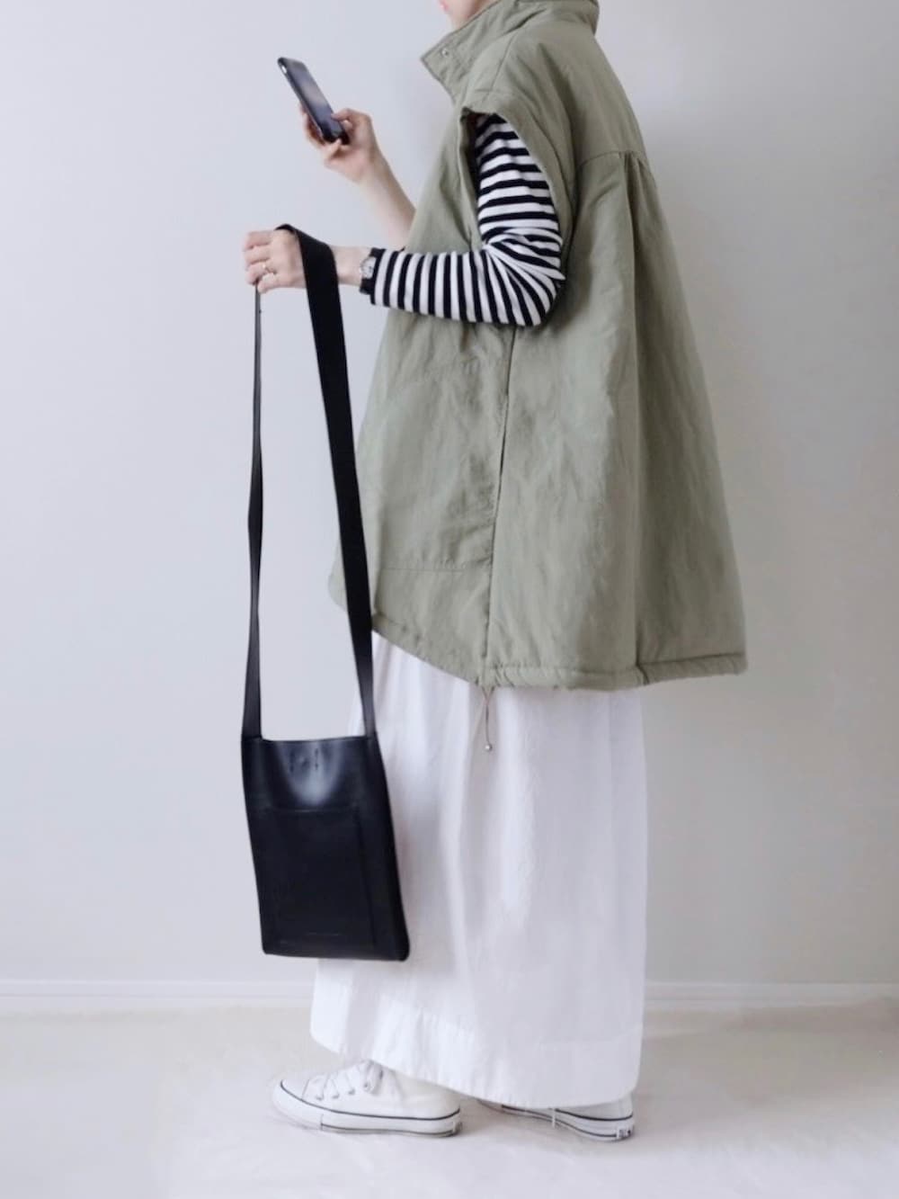 ブラック系のTシャツ/カットソー、ホワイト系のスカート、ホワイト系のスニーカーを着用したレディースの秋コーディネートの2枚目の写真