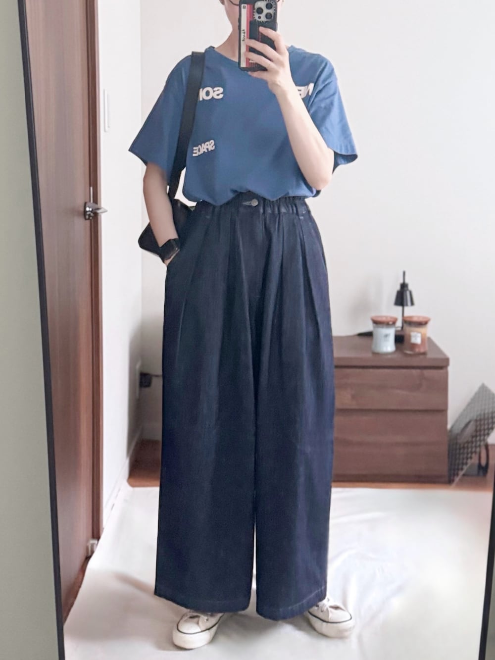 ブラック系のショルダーバッグ、ブルー系のTシャツ/カットソー、ブルー系のデニムパンツを着用したレディースの秋コーディネートの2枚目の写真