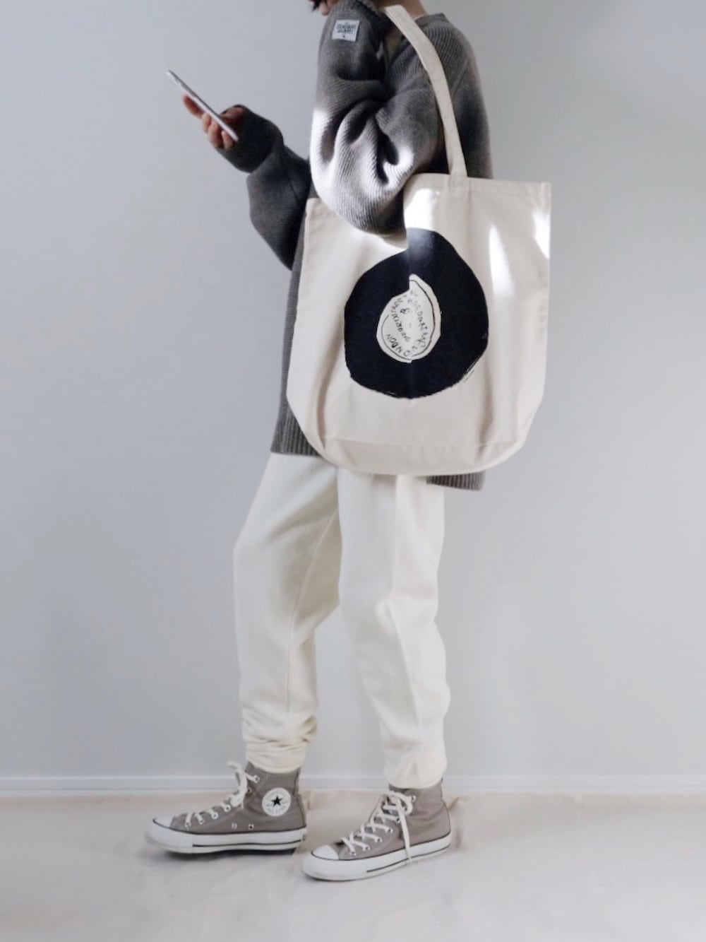 グレー系のニット/セーター、グレー系のスニーカー、イエロー系のマフラーを着用したレディースの冬コーディネートの2枚目の写真