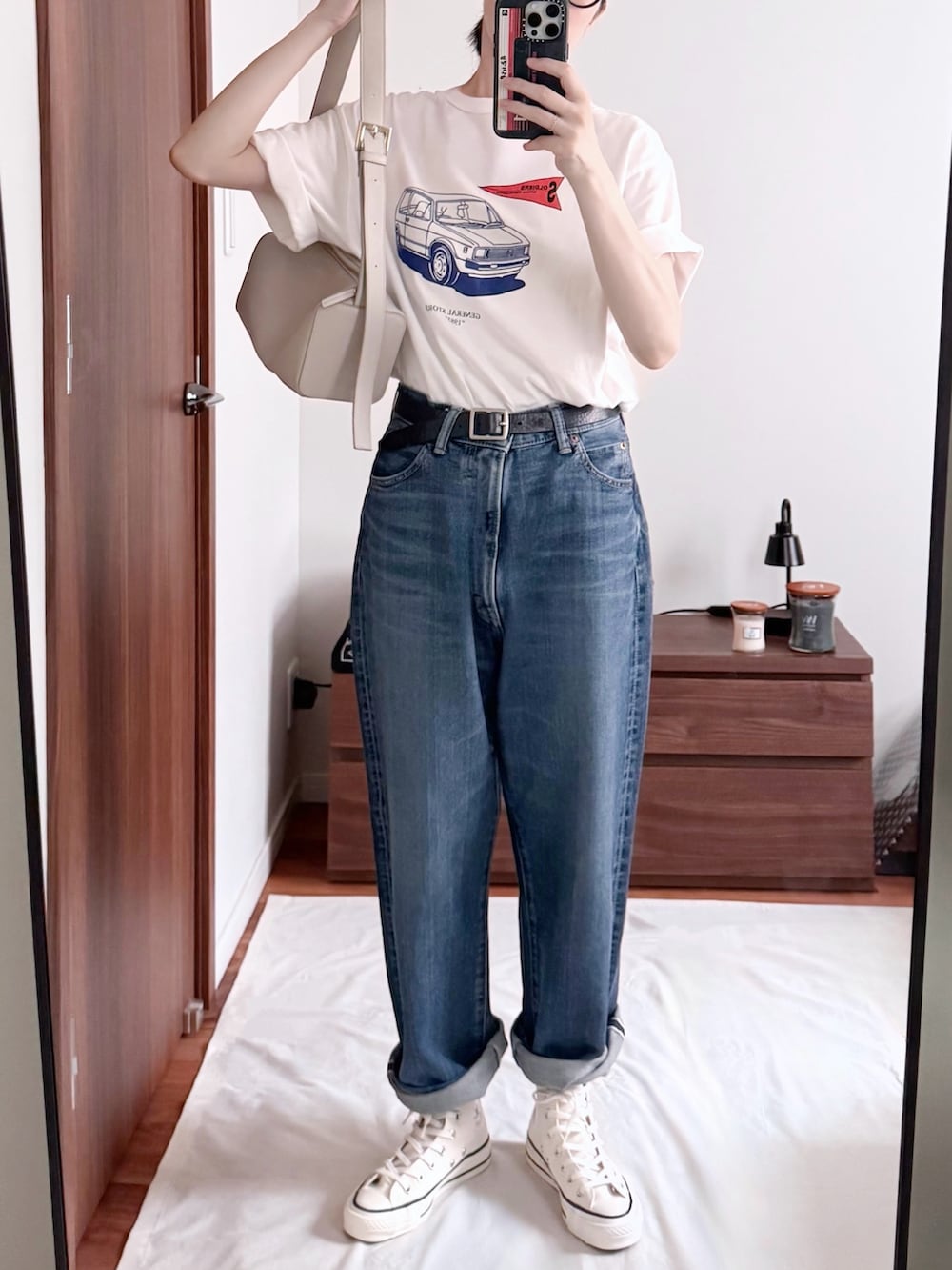 ホワイト系のスニーカー、ブルー系のデニムパンツ、ホワイト系のショルダーバッグを着用したレディースの夏コーディネートの2枚目の写真