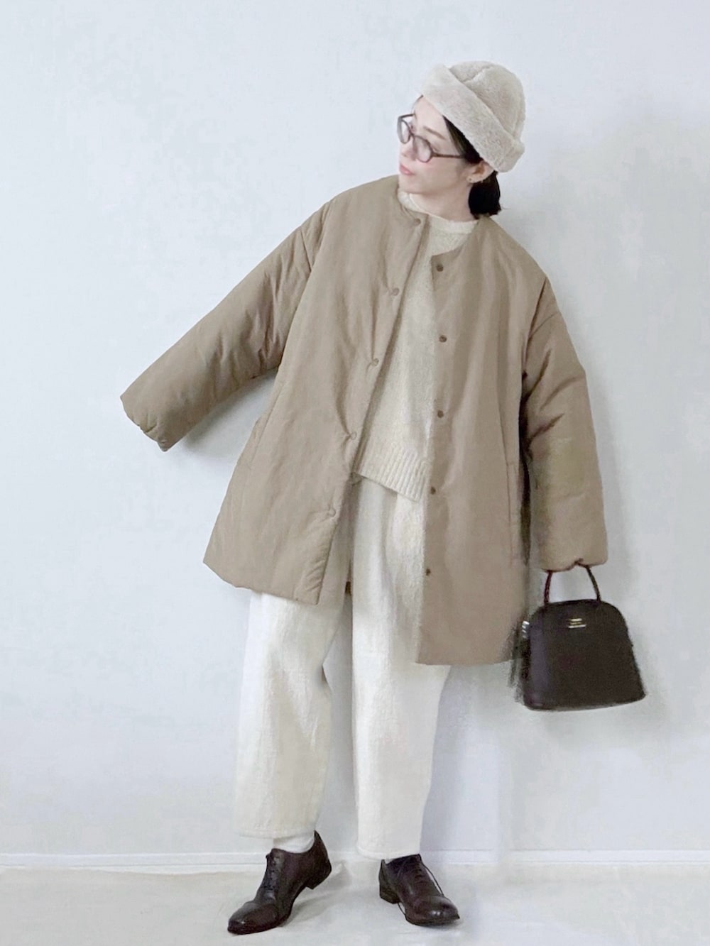 ブラウン系のハンドバッグ、ホワイト系のハットを着用したレディースの冬コーディネートの2枚目の写真