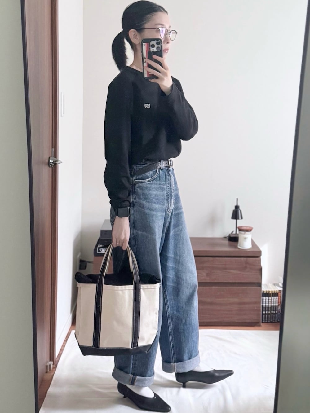 ブラック系のTシャツ/カットソー、ブルー系のデニムパンツ、ブラック系のパンプスを着用したレディースの秋コーディネートの3枚目の写真