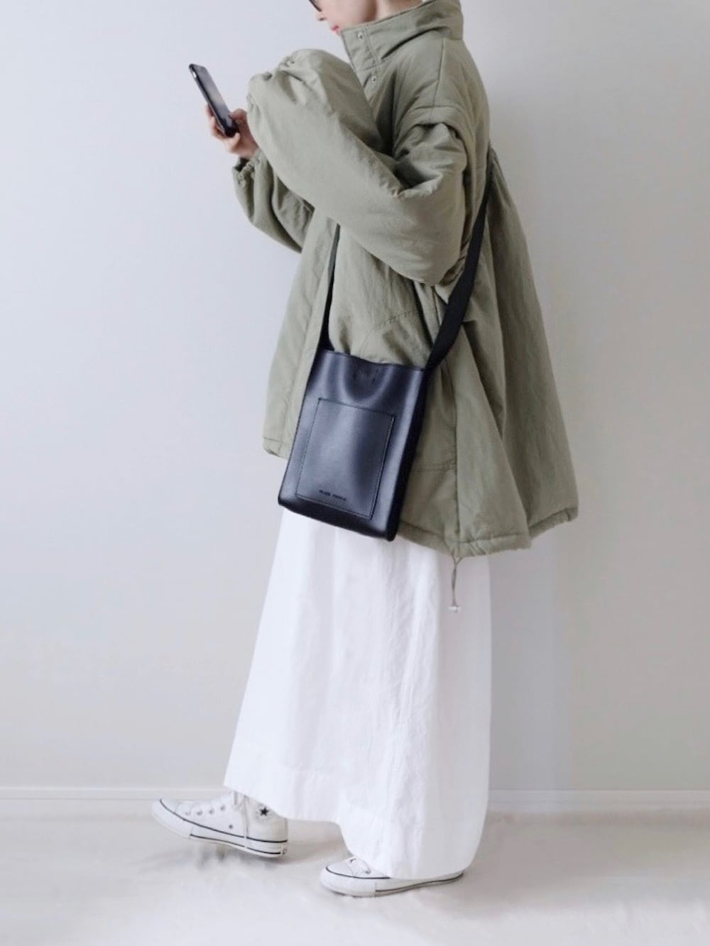 ブラック系のTシャツ/カットソー、ホワイト系のスカート、ホワイト系のスニーカーを着用したレディースの秋コーディネートの4枚目の写真