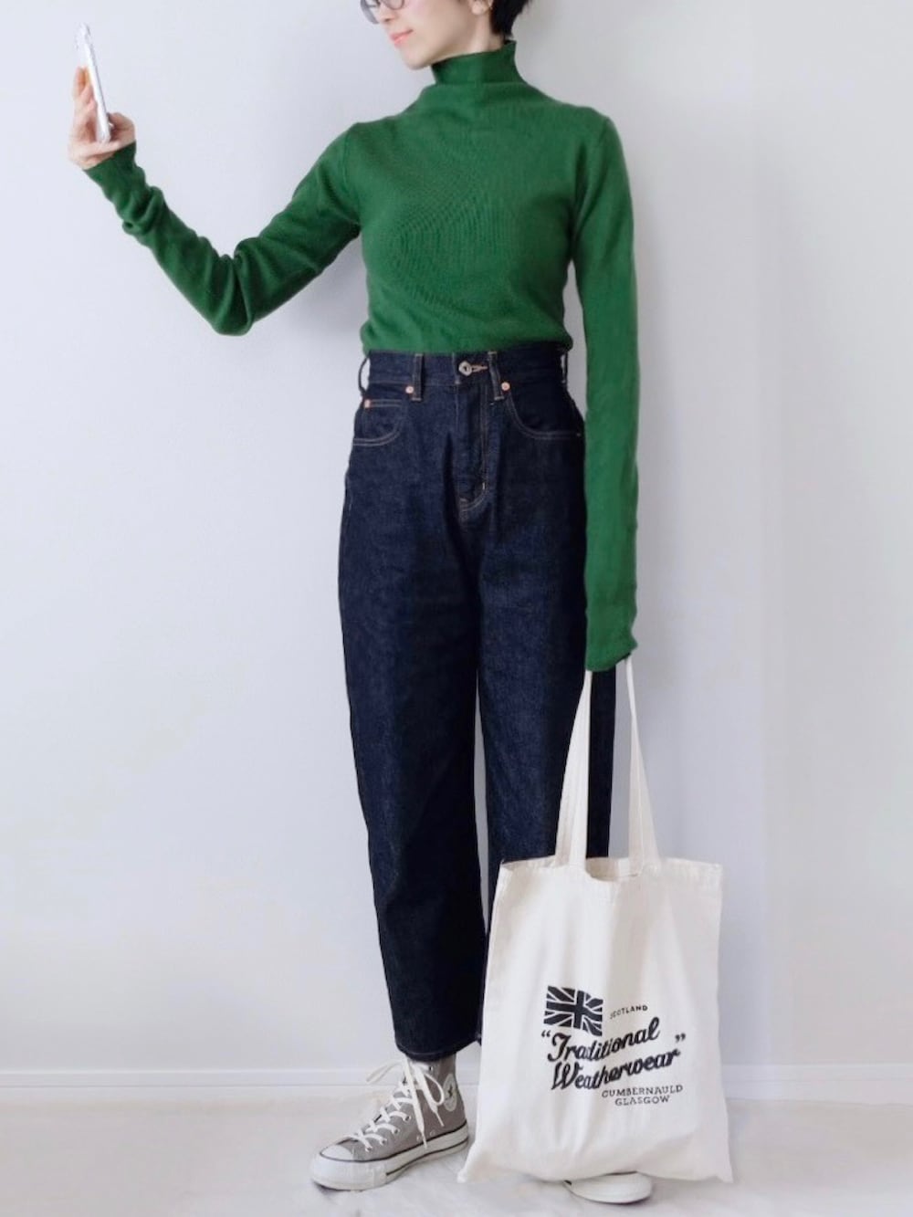 ブルー系のデニムパンツ、グレー系のスニーカー、ホワイト系のトートバッグを着用したレディースの冬コーディネートの2枚目の写真