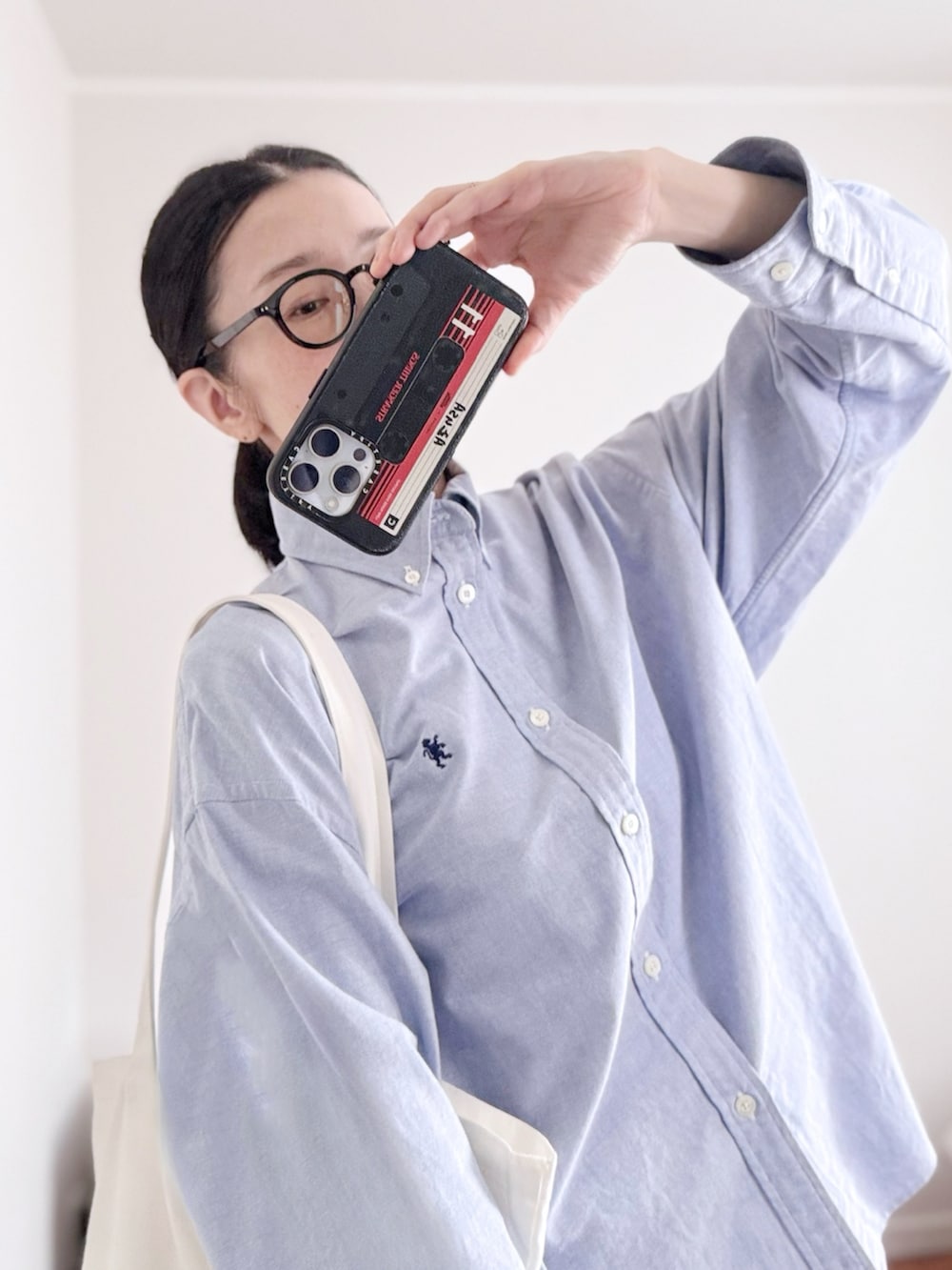 ブルー系のシャツ/ブラウス、ブルー系のデニムパンツ、ホワイト系のトートバッグを着用したレディースの秋コーディネートの4枚目の写真