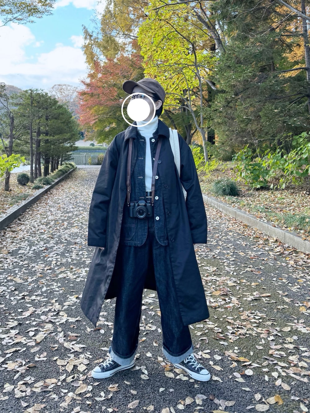 ブラック系のステンカラーコート、ブルー系のカバーオール、ブルー系のデニムパンツを着用したレディースの秋コーディネートの3枚目の写真