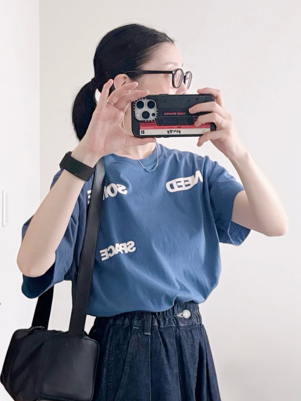 ブラック系のショルダーバッグ、ブルー系のTシャツ/カットソー、ブルー系のデニムパンツを着用したレディースの秋コーディネートの3枚目の写真