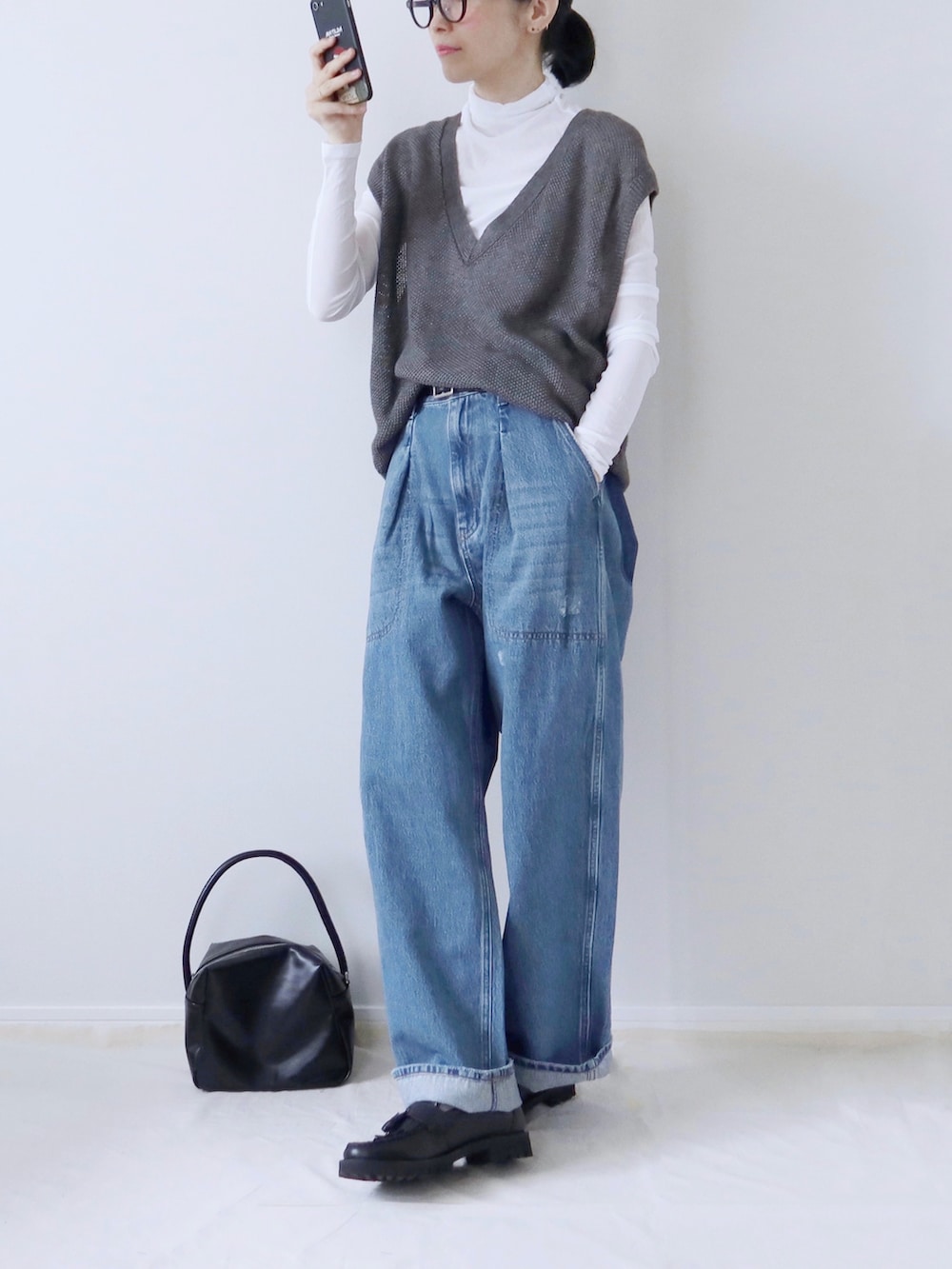 グレー系のニット/セーター、ホワイト系のTシャツ/カットソー、ブルー系のデニムパンツを着用したレディースの秋コーディネートの2枚目の写真