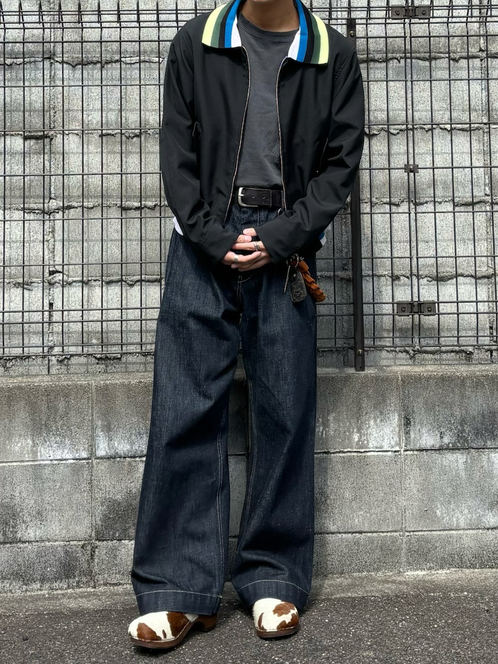 ブラック系のブルゾン、ブルー系のデニムパンツ、ブラウン系のサンダルを着用したメンズの春コーディネートの2枚目の写真